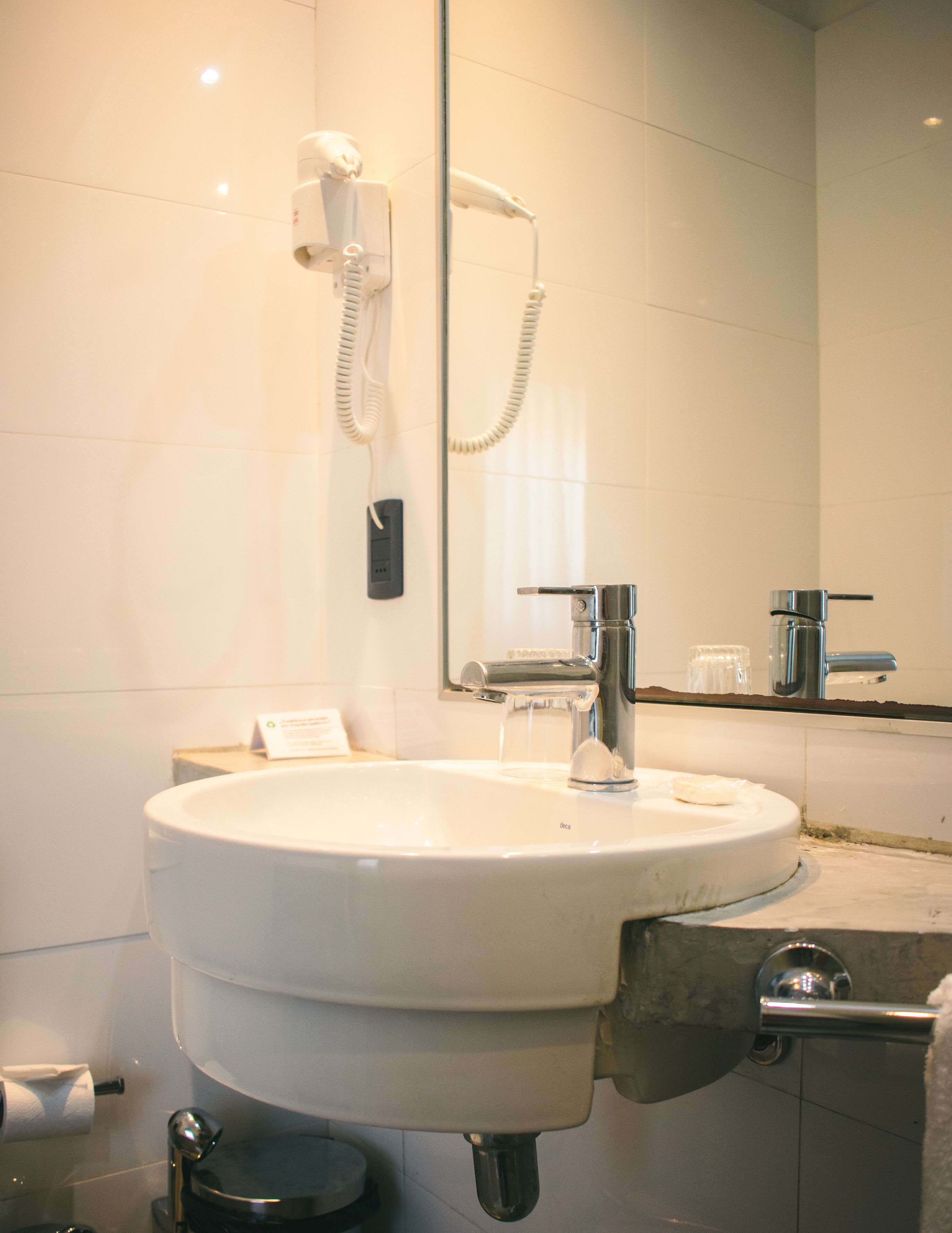 A bathroom with a white sink, a mirror, a handheld showerhead, and a towel rack.