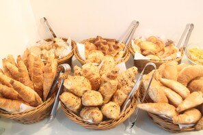 Una mesa de buffet con diferentes tipos de pan y pasteles dispuestos en cestas.
