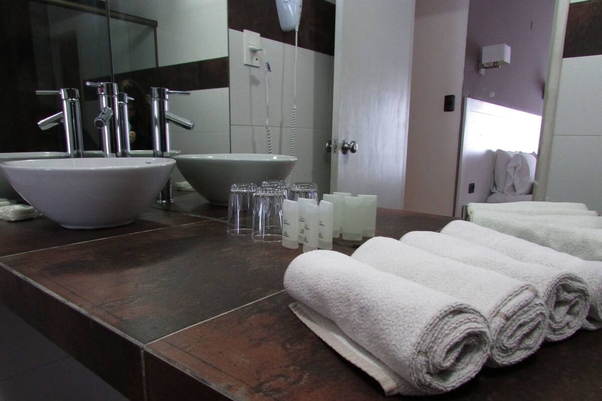 A bathroom with a large sink, a bathtub, and a mirror. There are towels and toiletries on the counter.