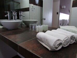 Un baño con un lavamanos grande, una bañera y un espejo. Hay toallas y artículos de aseo en la encimera.