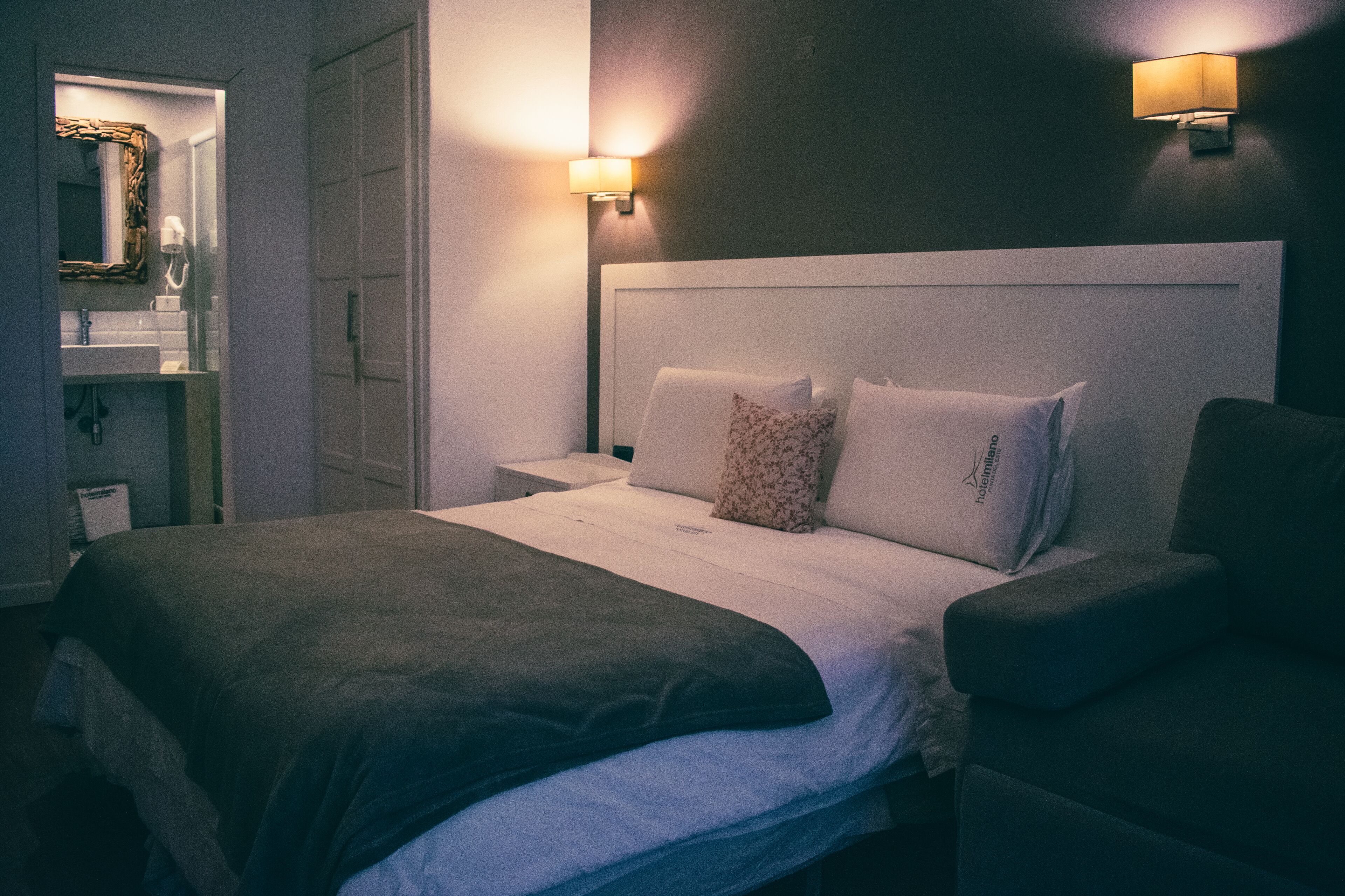 Una habitación de hotel con una cama grande, dos lámparas de noche, una mesita de noche y un armario.