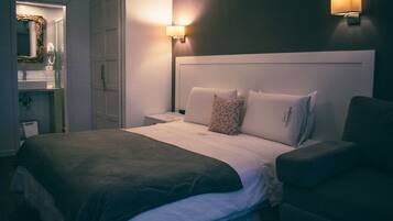 Una habitación de hotel con una cama grande, dos lámparas de noche, una mesita de noche y un armario.