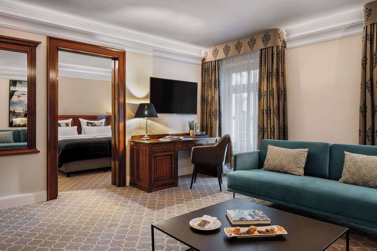 A hotel room with a bed, a desk, a green sofa, and a coffee table.