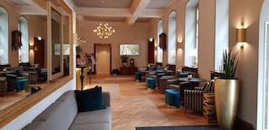 A hotel lobby with a central seating area, multiple tables, and a large mirror. - Parkhotel Engelsburg (Recklinghausen)