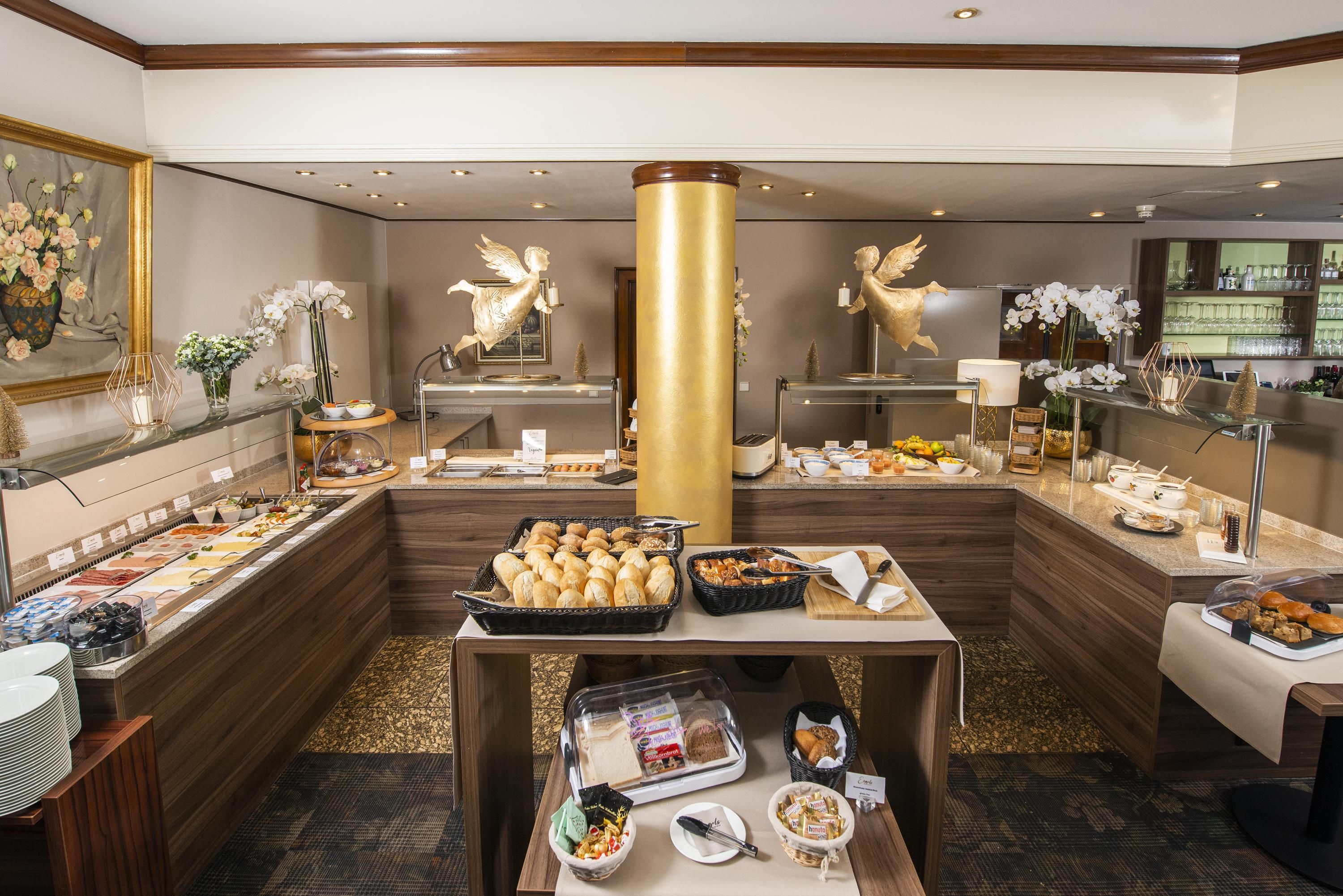 A buffet area with various food options, a central gold pillar, and decorative angel statues.