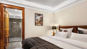 A hotel room with a bed, a nightstand, a lamp, a shower area, and a door. - Parkhotel Engelsburg (Recklinghausen)