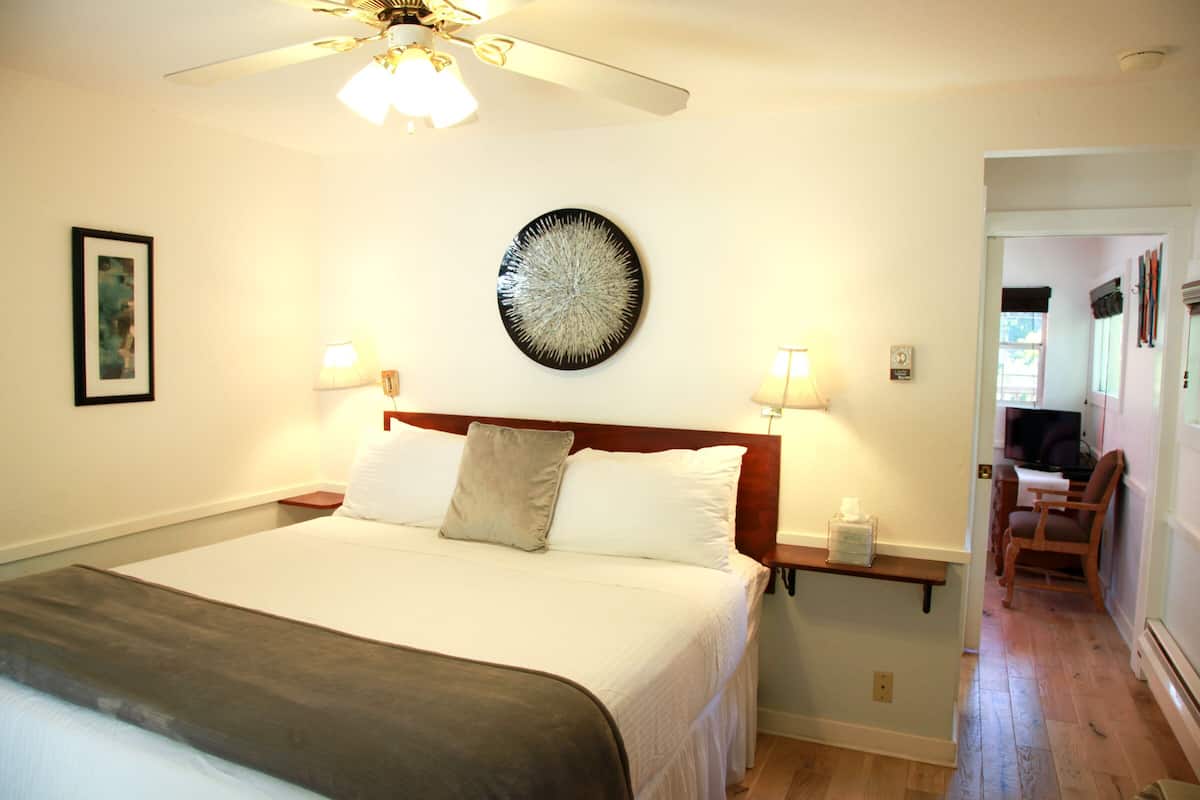 A neatly made bed with a headboard, bedside lamps, and a ceiling fan.