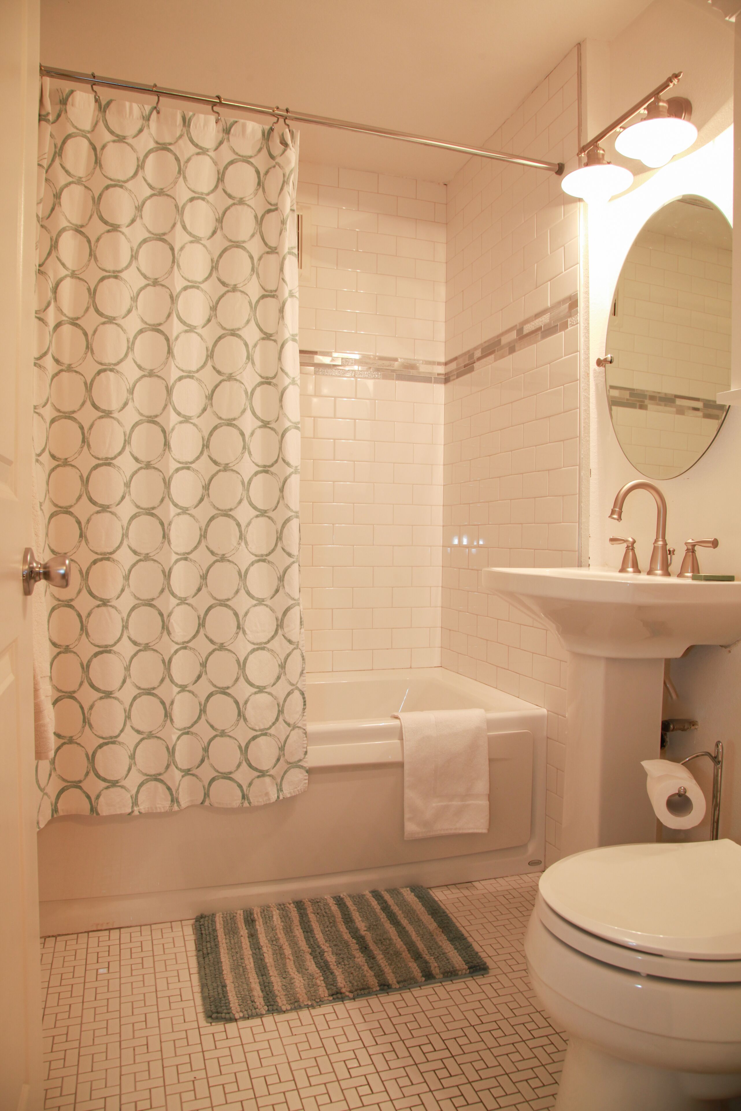 A bathroom with a shower, toilet, sink, and a mirror.