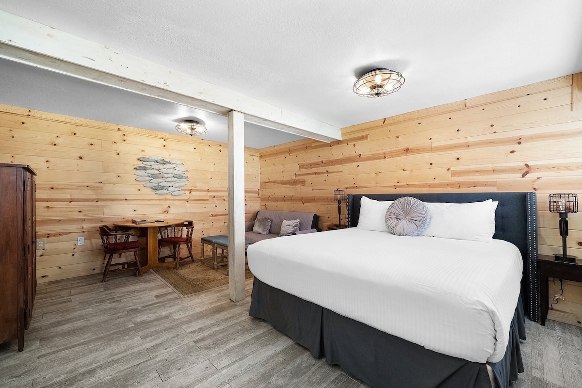 A wooden-paneled bedroom with a bed, a desk, and a chair.