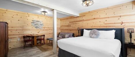 A wooden-paneled bedroom with a bed, a desk, and a chair.
