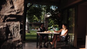 Un espace extérieur aménagé pour les repas, avec un mur en pierre, une table et des chaises.