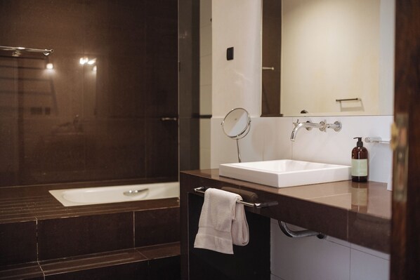 A modern bathroom with a large mirror, a white sink, and a shower area.