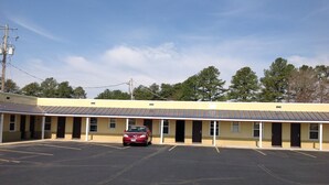A motel with a parking lot and a red car parked in front. - Budget Inn (Salisbury)