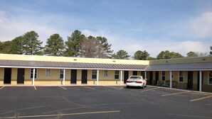 A motel with a row of rooms, a parking lot, and a car parked in front. - Budget Inn (Salisbury)