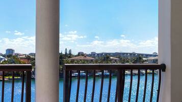 A balcony with a view of a body of water, a chair, and a column.