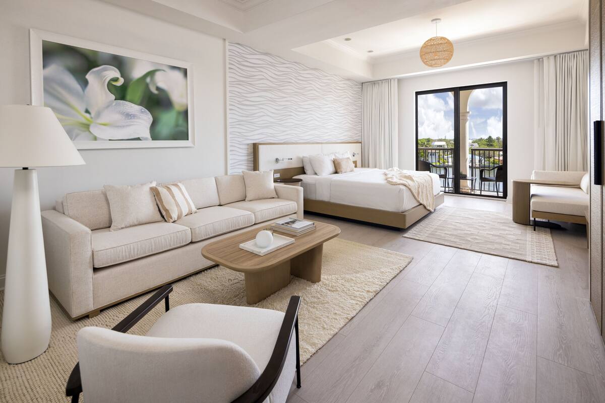Une chambre d’hôtel moderne avec un canapé, un lit, une table basse et un balcon offrant une vue agréable.