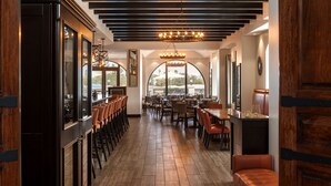 Un restaurante con una barra alargada, varias áreas de estar y vistas amplias a través de grandes ventanales.