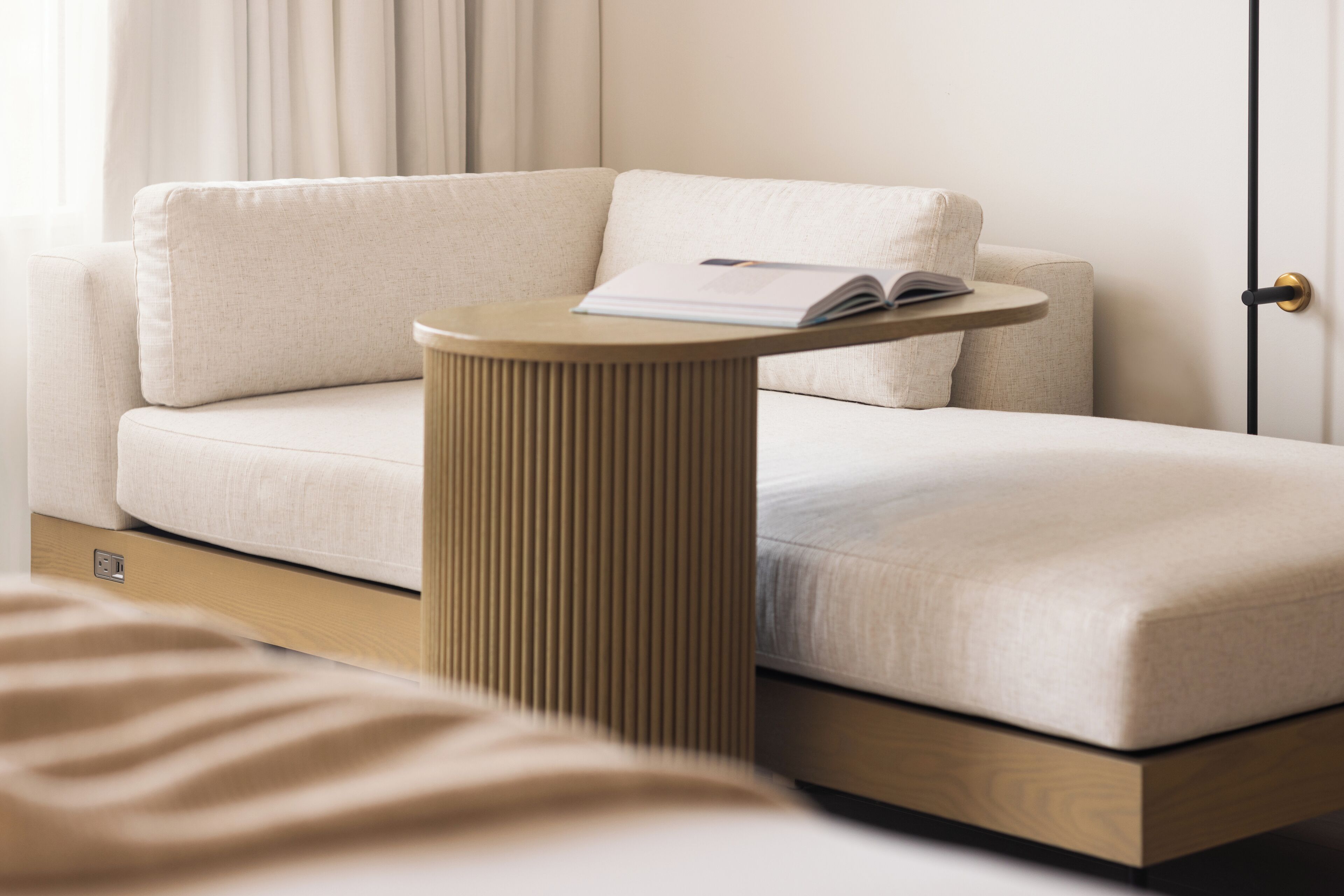 Ein modernes Zimmer mit einer Couch, einem kleinen runden Tisch mit einem Buch und Holzboden.