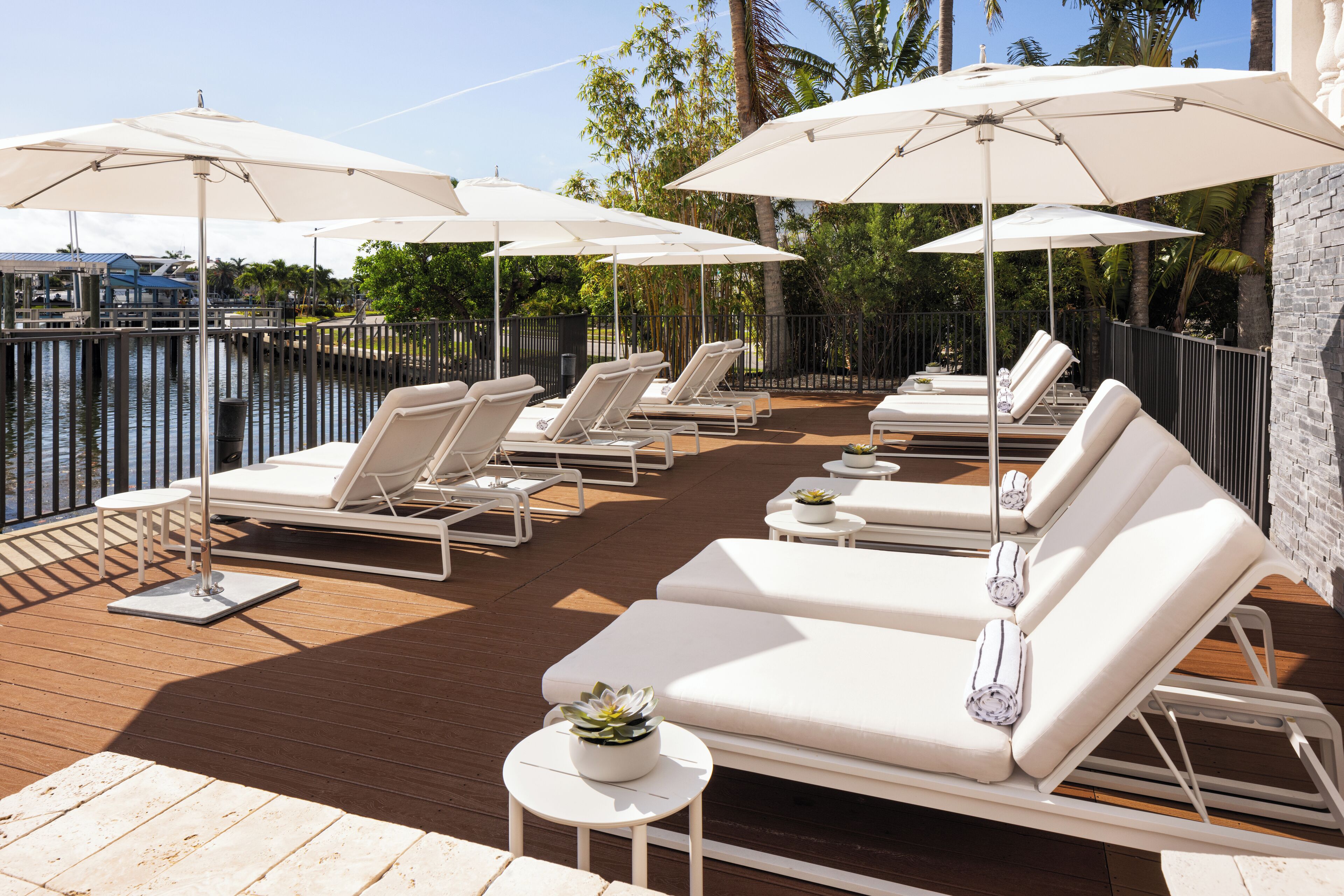 A deck with sun loungers and umbrellas, overlooking a body of water.