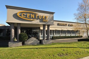 A Century Inn hotel with a prominent sign, large columns, and a well-maintained lawn.