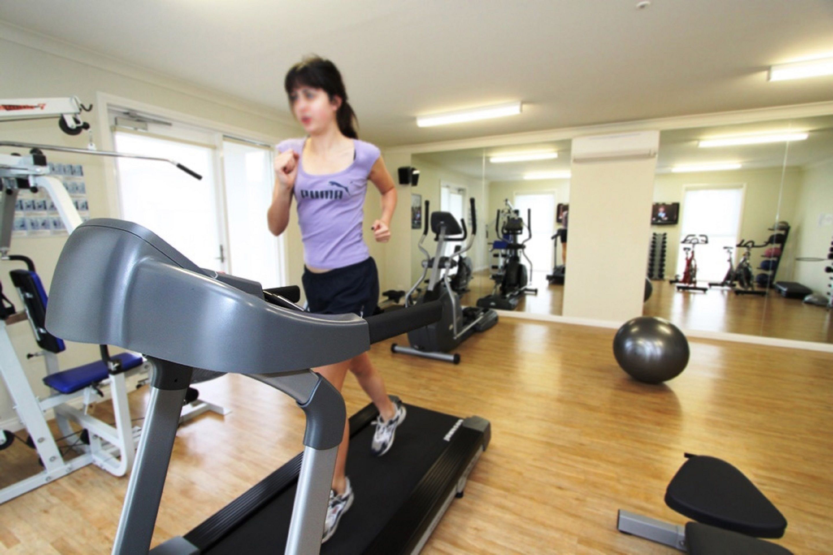 Une salle de sport équipée de tapis de course, de ballons d’exercice et de divers appareils de musculation.