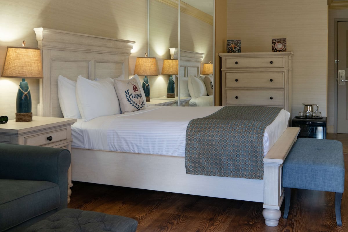 A neatly arranged bedroom with a large bed, bedside tables, a dresser, and a bench.