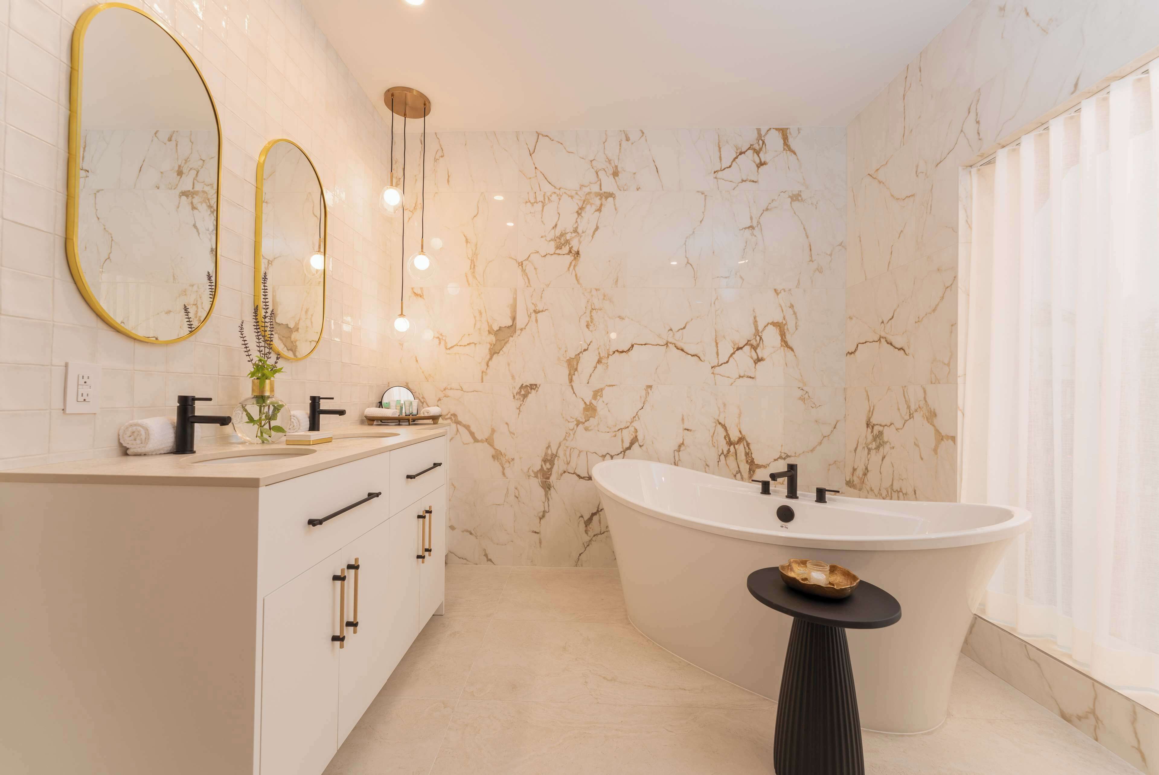 A modern bathroom with a freestanding bathtub, a vanity with a mirror, and a small table with a bowl.
