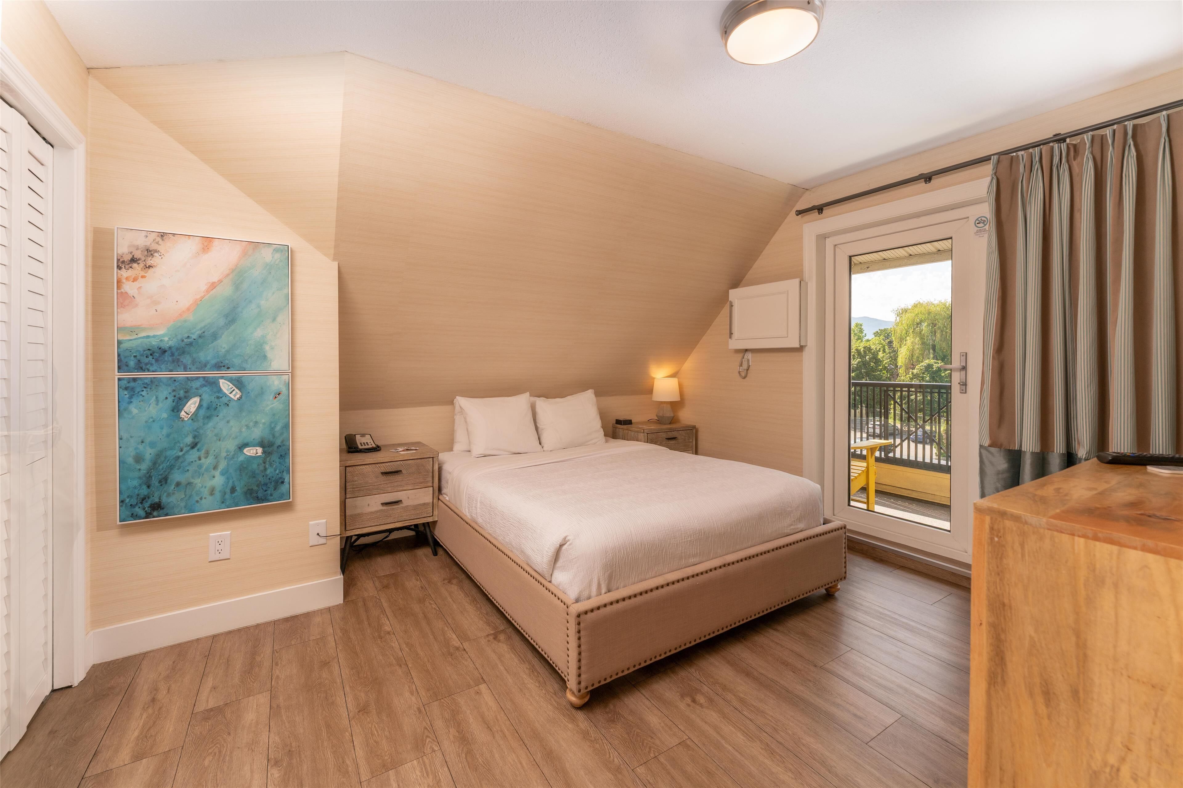 Ein Schlafzimmer mit Bett, Nachttischen, Vorhängen am Fenster und einem Bild an der Wand.