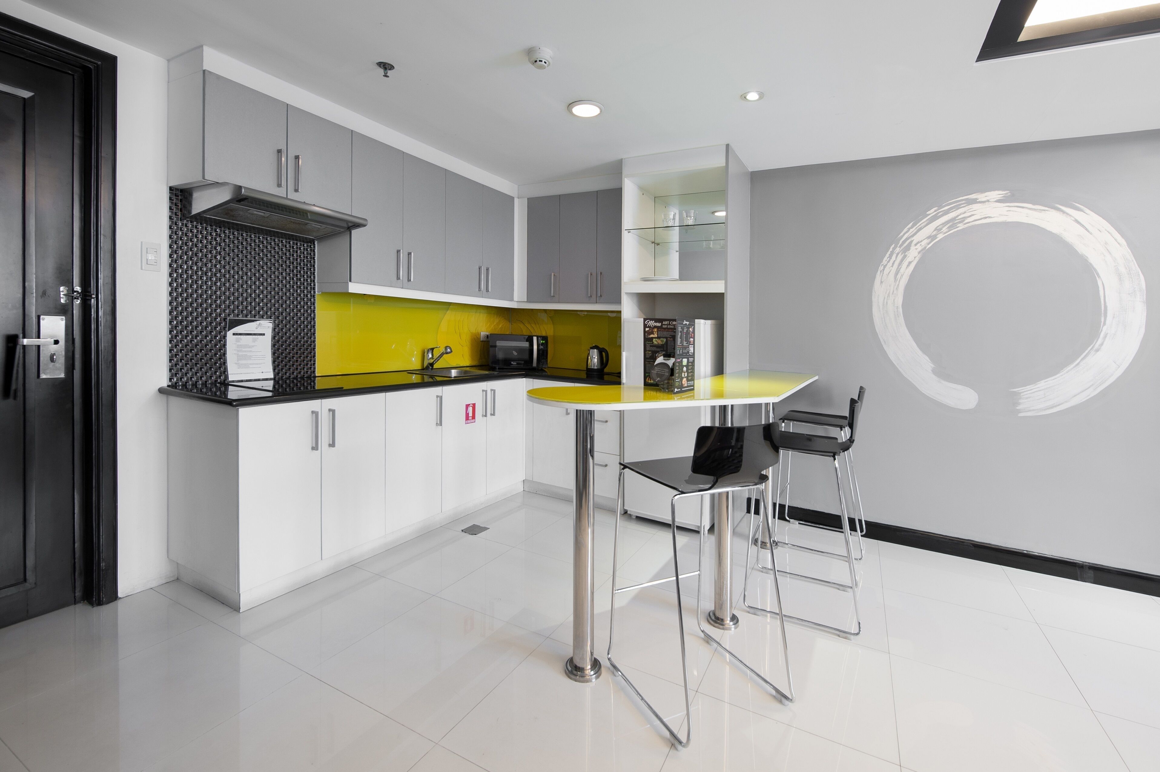 Une cuisine moderne avec un plan de travail jaune, des appareils en acier inoxydable et un design minimaliste.