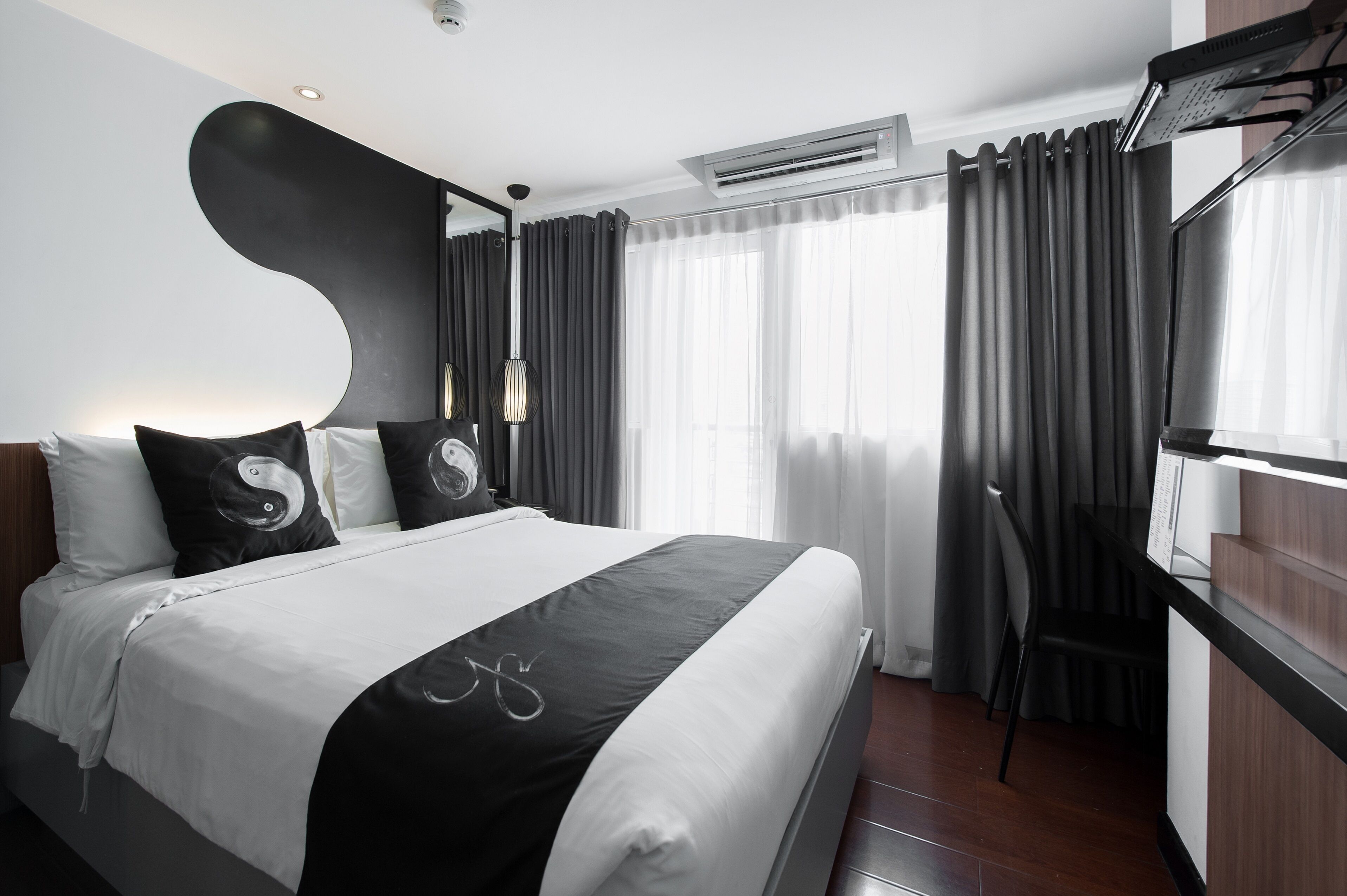 A modern hotel room with a large bed, a flat-screen TV, and a desk with a chair.