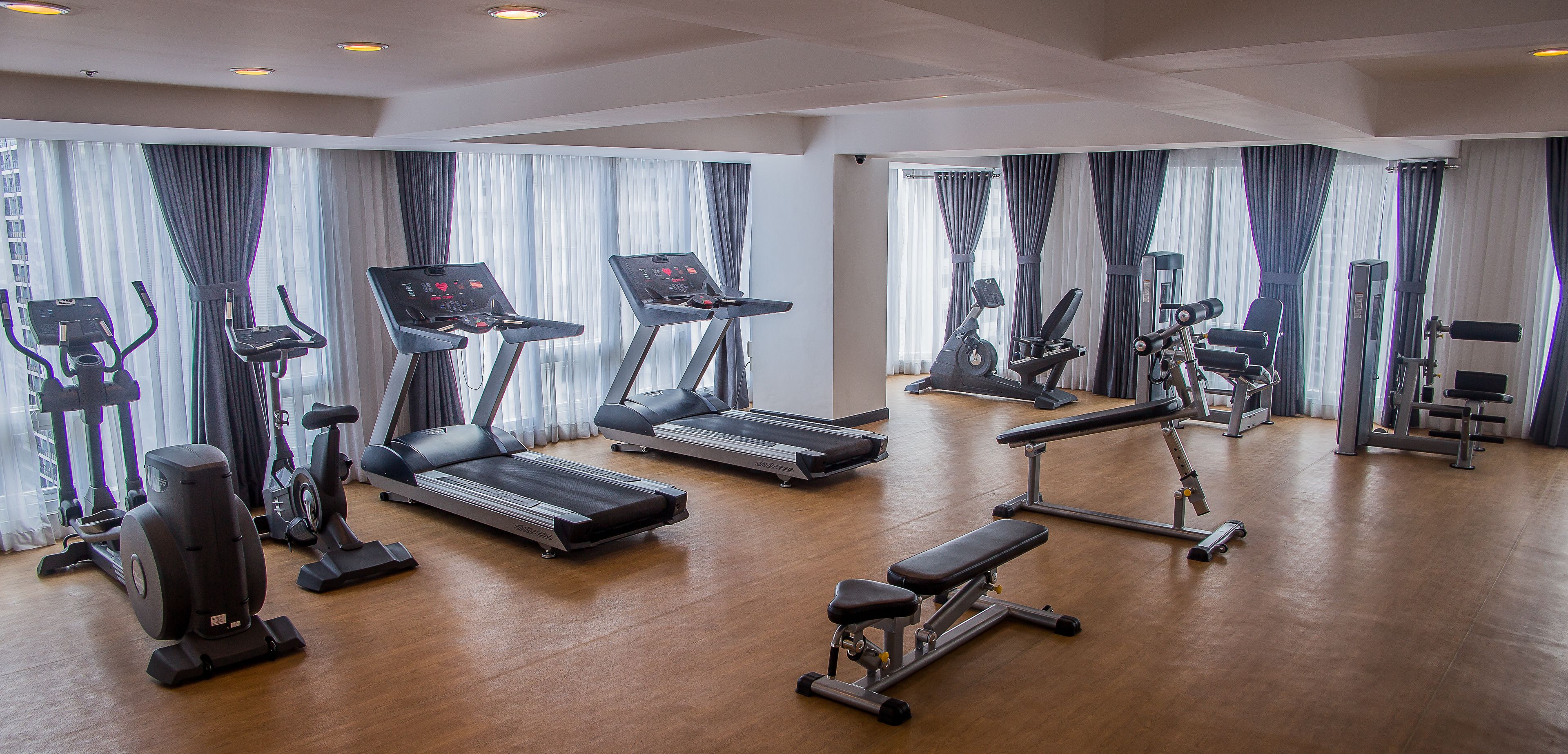 A spacious gym with various exercise equipment including treadmills, elliptical machines, and weight benches.