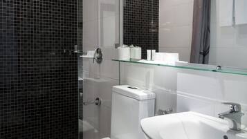 A modern bathroom with a glass shower enclosure, a white toilet, and a sink with a mirror above it.