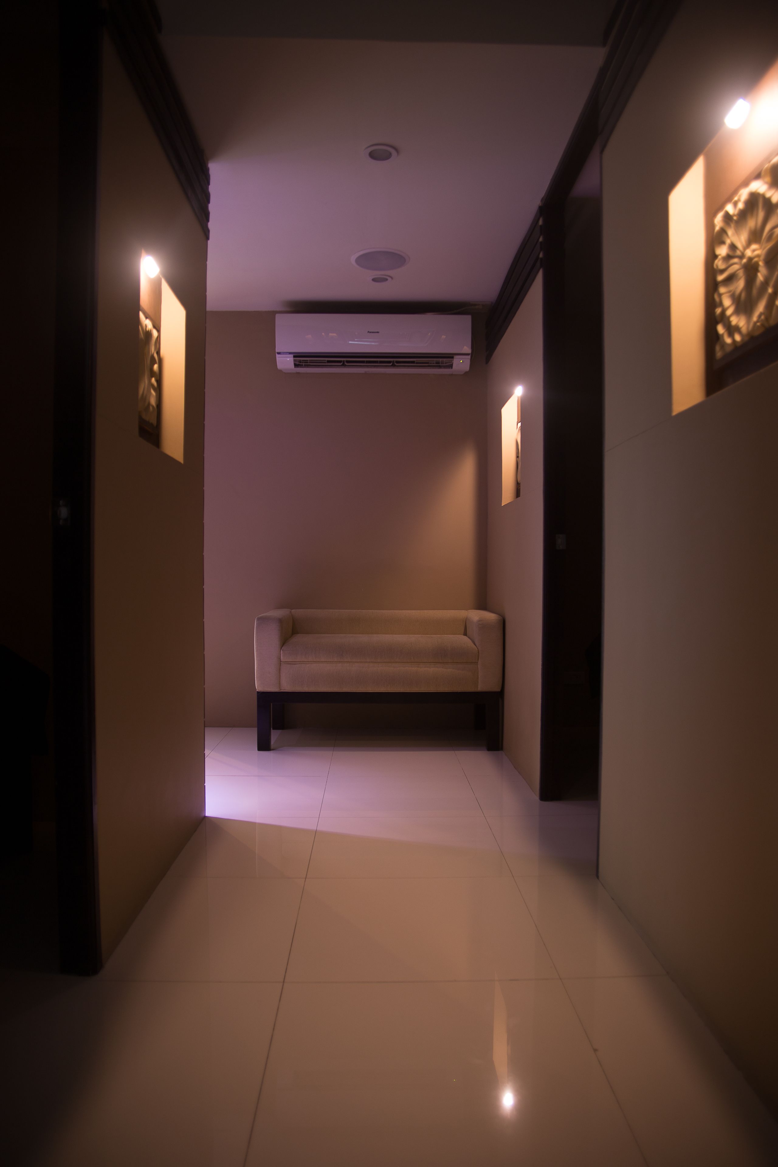 Um corredor com sofá, iluminação embutida e ar condicionado.