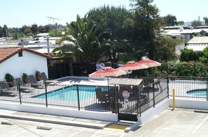 A rooftop pool area with a fenced pool, outdoor seating, and umbrellas.