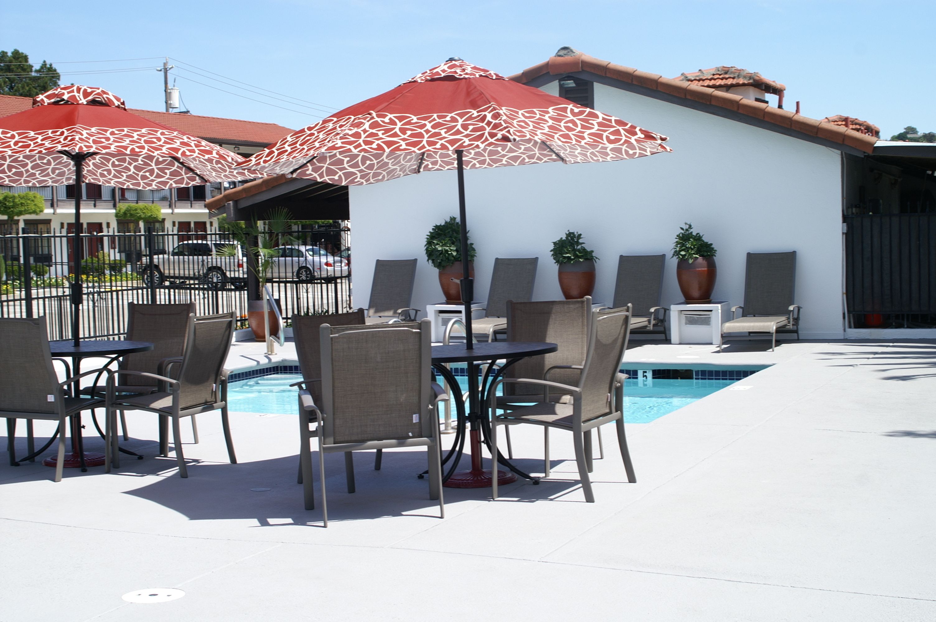 Um pátio externo com piscina, espreguiçadeiras e guarda-sóis.