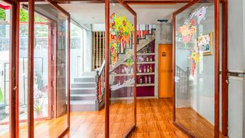 A hallway with glass doors, a wooden staircase, and shelves with bottles.