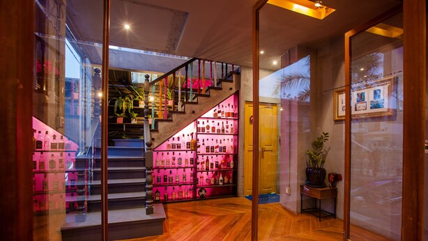 A staircase with a pink-lit shelf on the right, a wooden floor, and a glass door on the left. - Madam Inn Patong (Patong)
