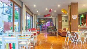 A spacious lobby with wooden flooring, a staircase, and a seating area with tables and chairs. - Madam Inn Patong (Patong)