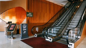 Vista interior de un vestíbulo de hotel con una escalera mecánica, una recepción e indicación 'Salas de función, nivel 1'.