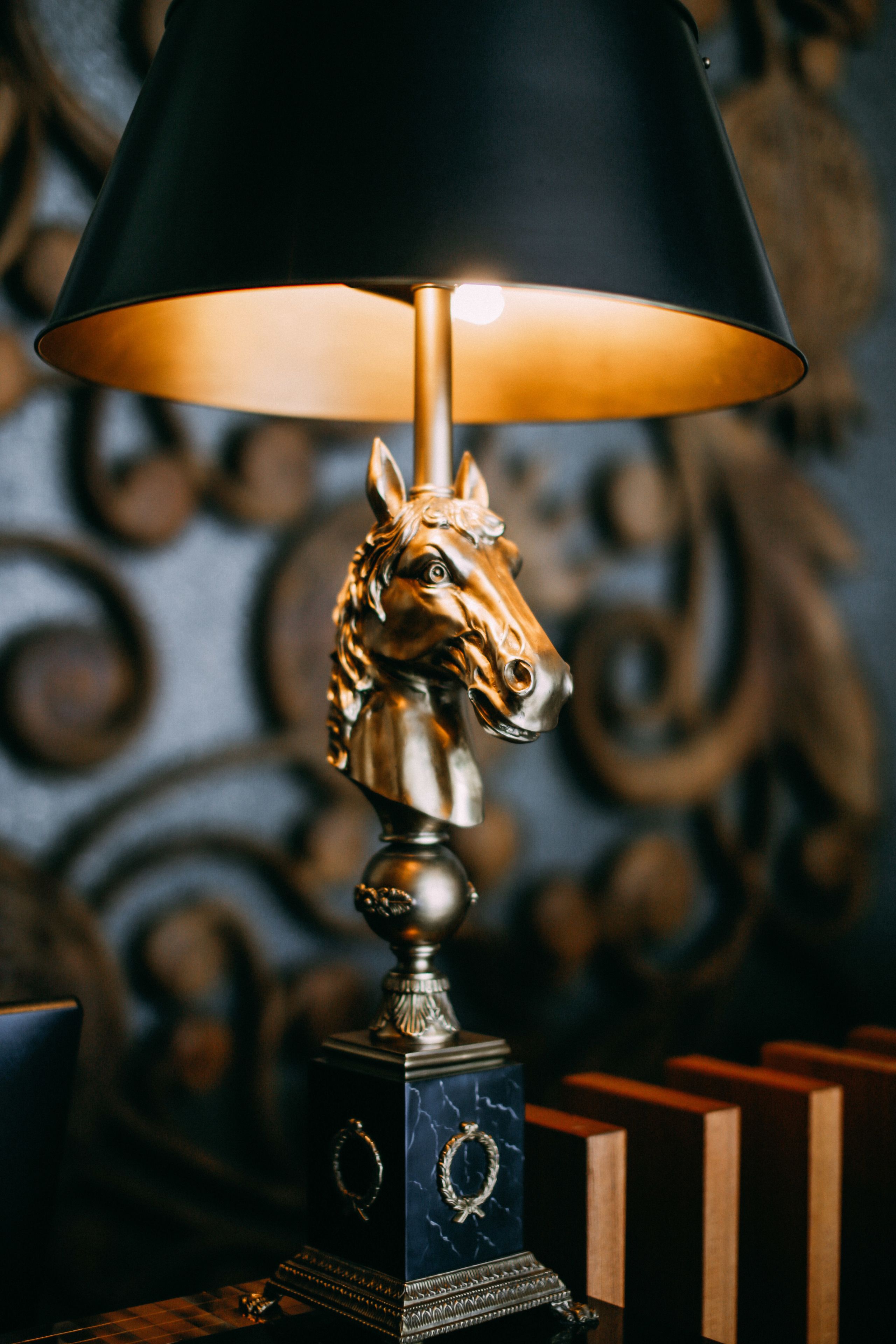 A lamp with a horse head base and a black shade.