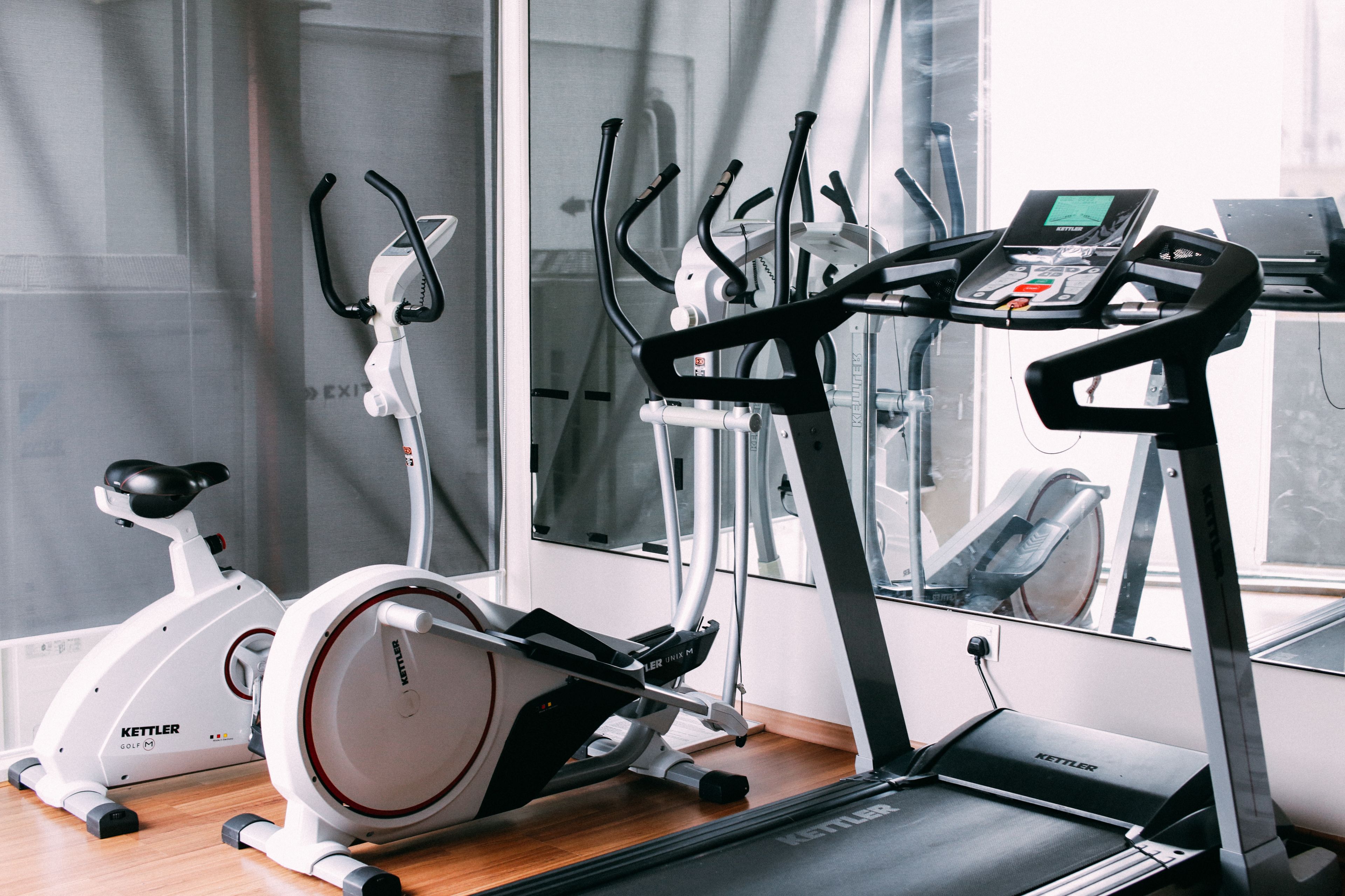 Een sportschool met een hometrainer, elliptische trainer en loopband.