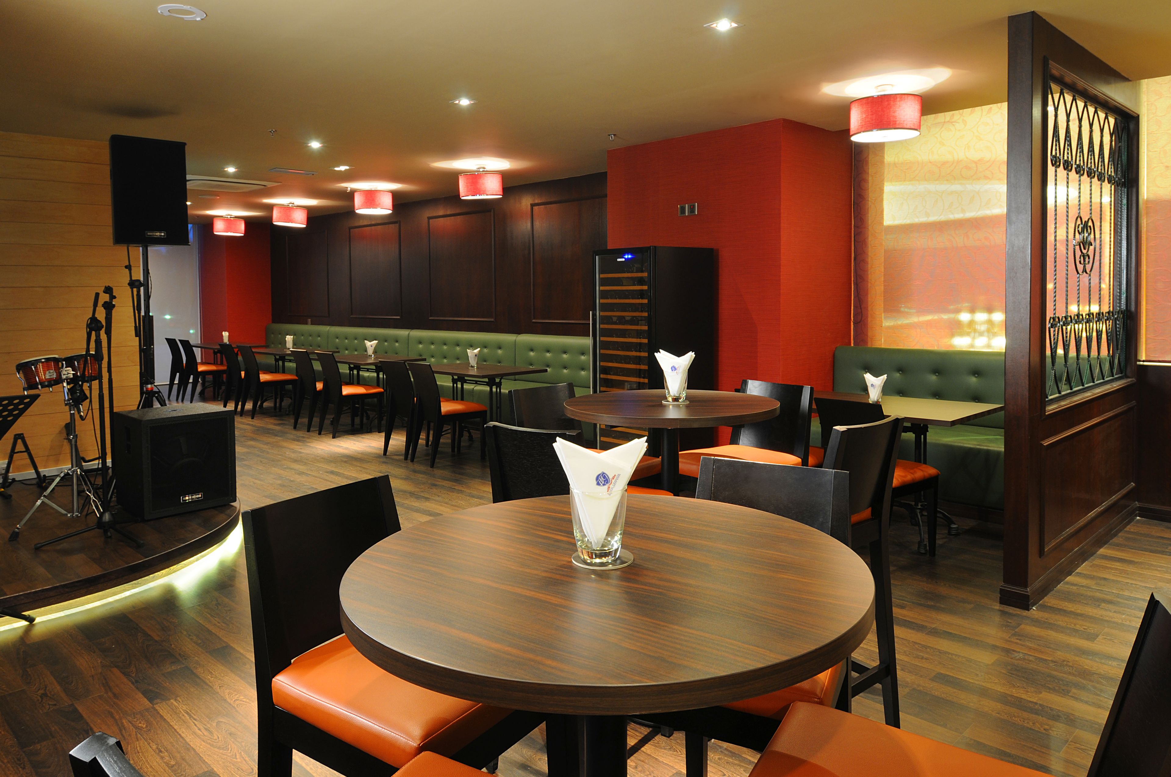 Un restaurant avec des tables rondes, des banquettes et des chaises orange.