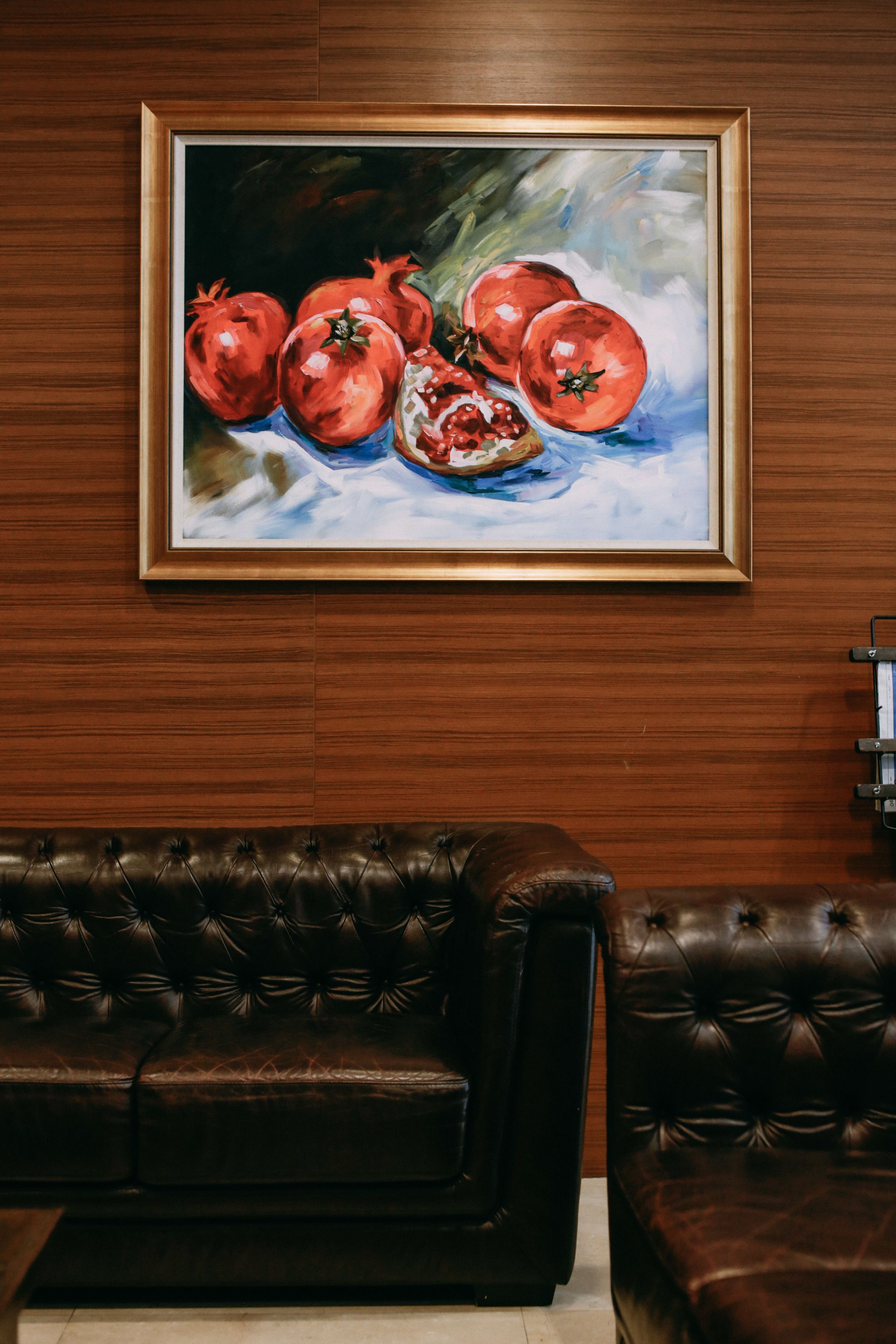 Un quadro incorniciato con melograni appeso a una parete di legno.
