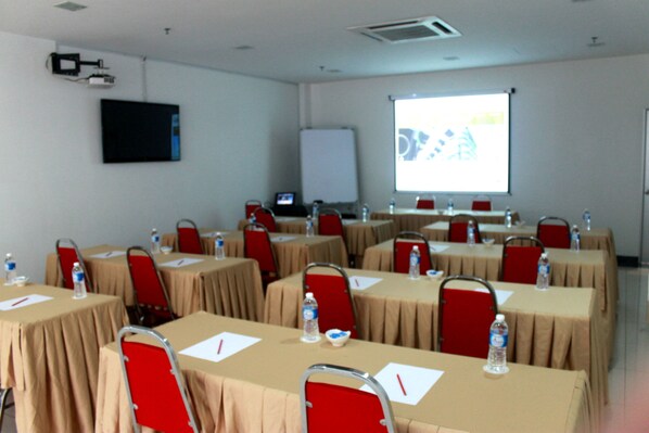 A conference room with multiple tables, each equipped with a laptop, water bottle, and notepad.