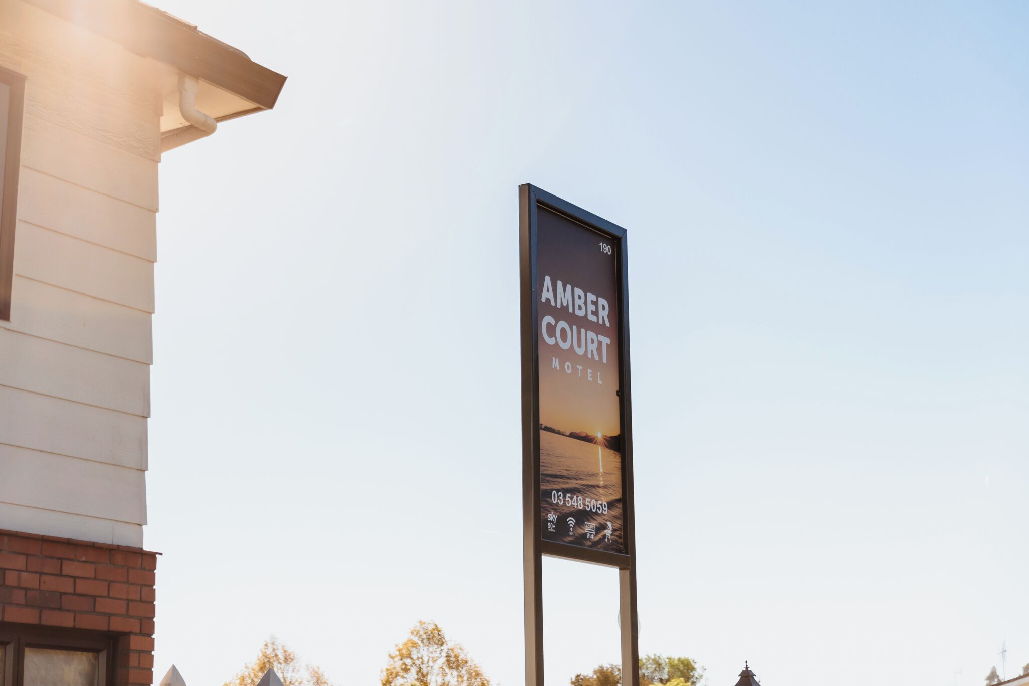 Naamplaatje voor het Amber Court Motel, met een telefoonnummer en pictogrammen voor voorzieningen.