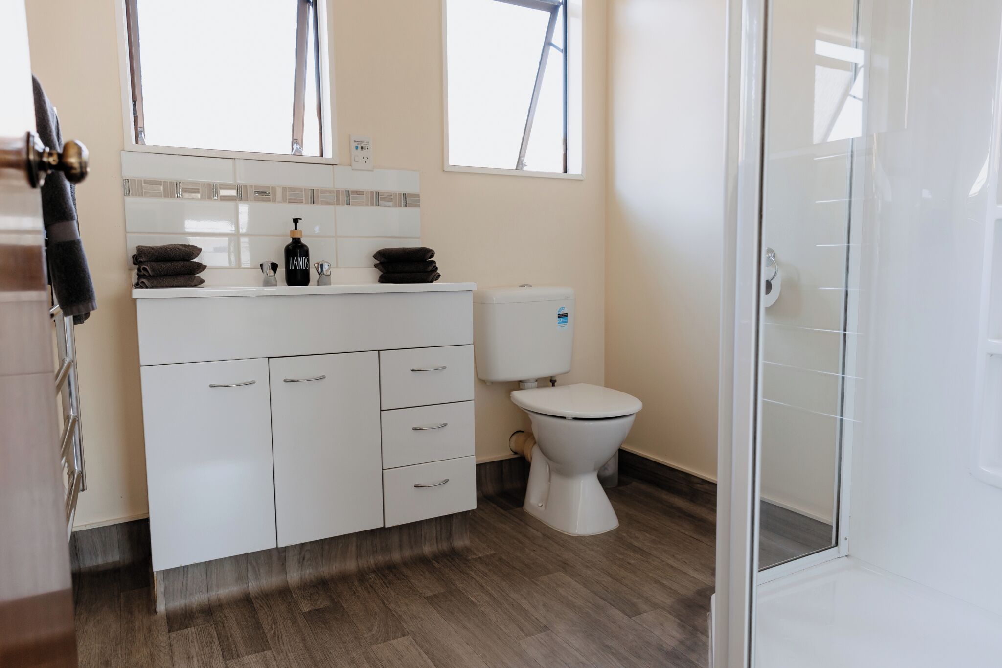 A modern bathroom with a white vanity, a toilet, and a glass shower enclosure.