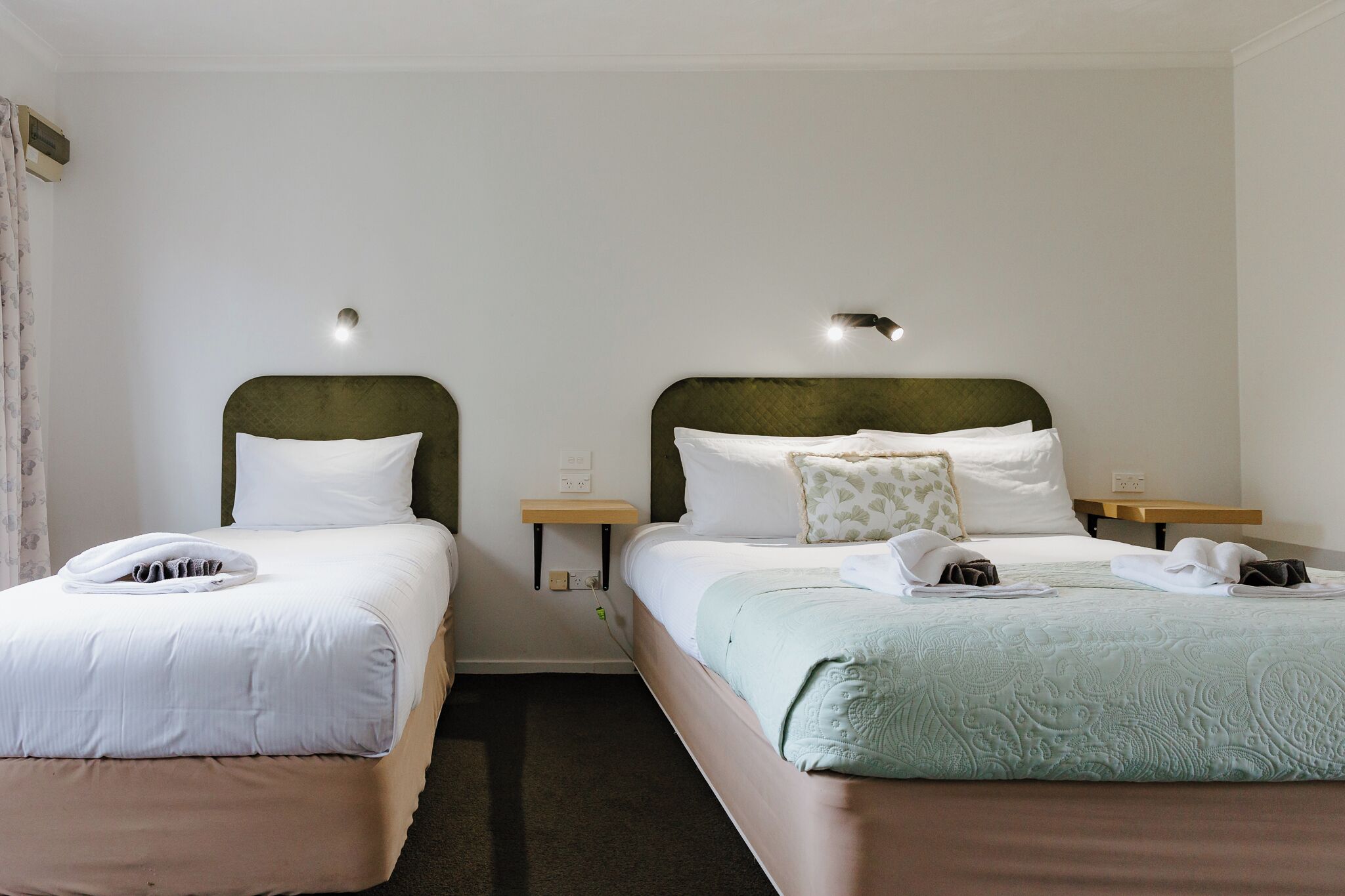 Two single beds with headboards, bedside tables, and lamps.