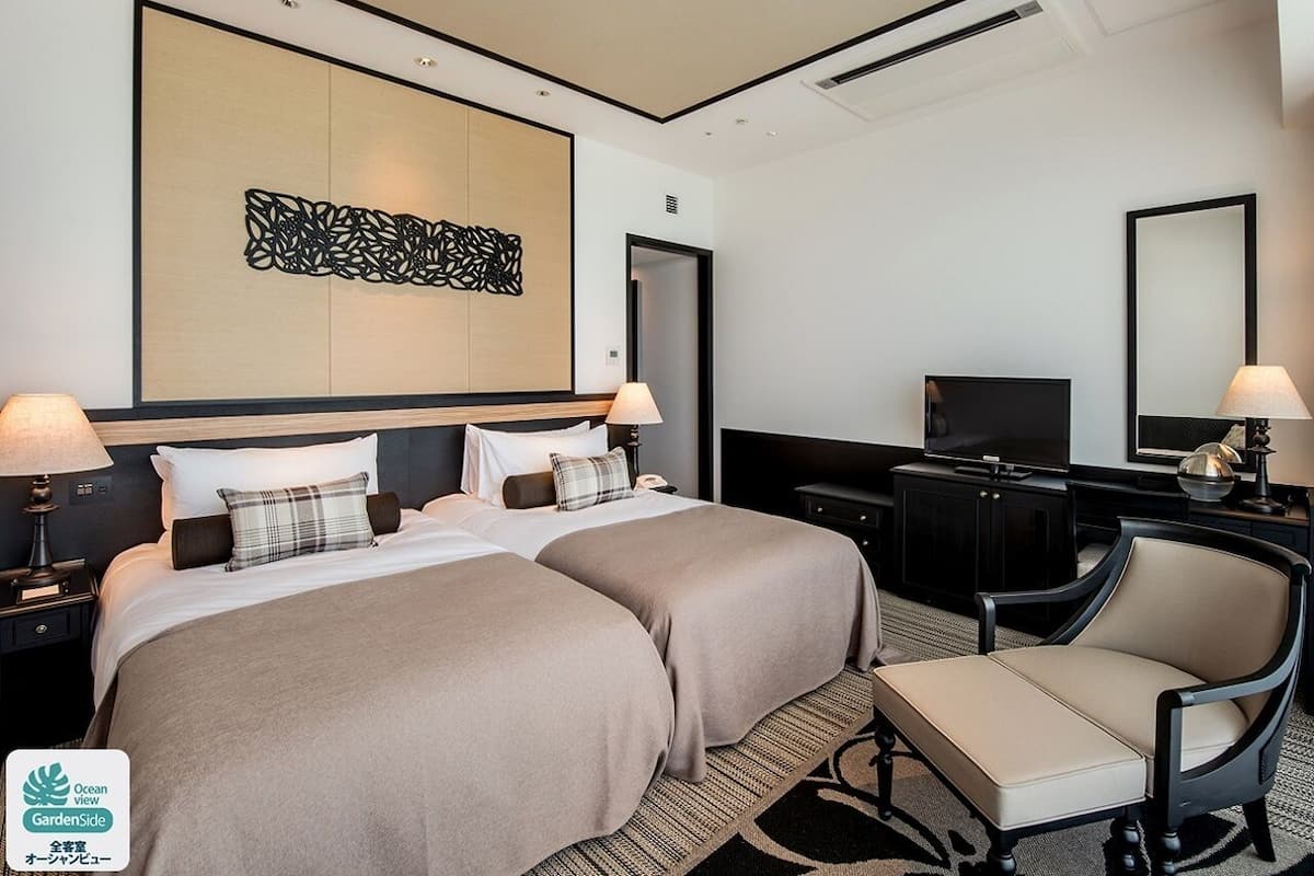Een hotelkamer met twee bedden, een bureau, een televisie en een stoel.