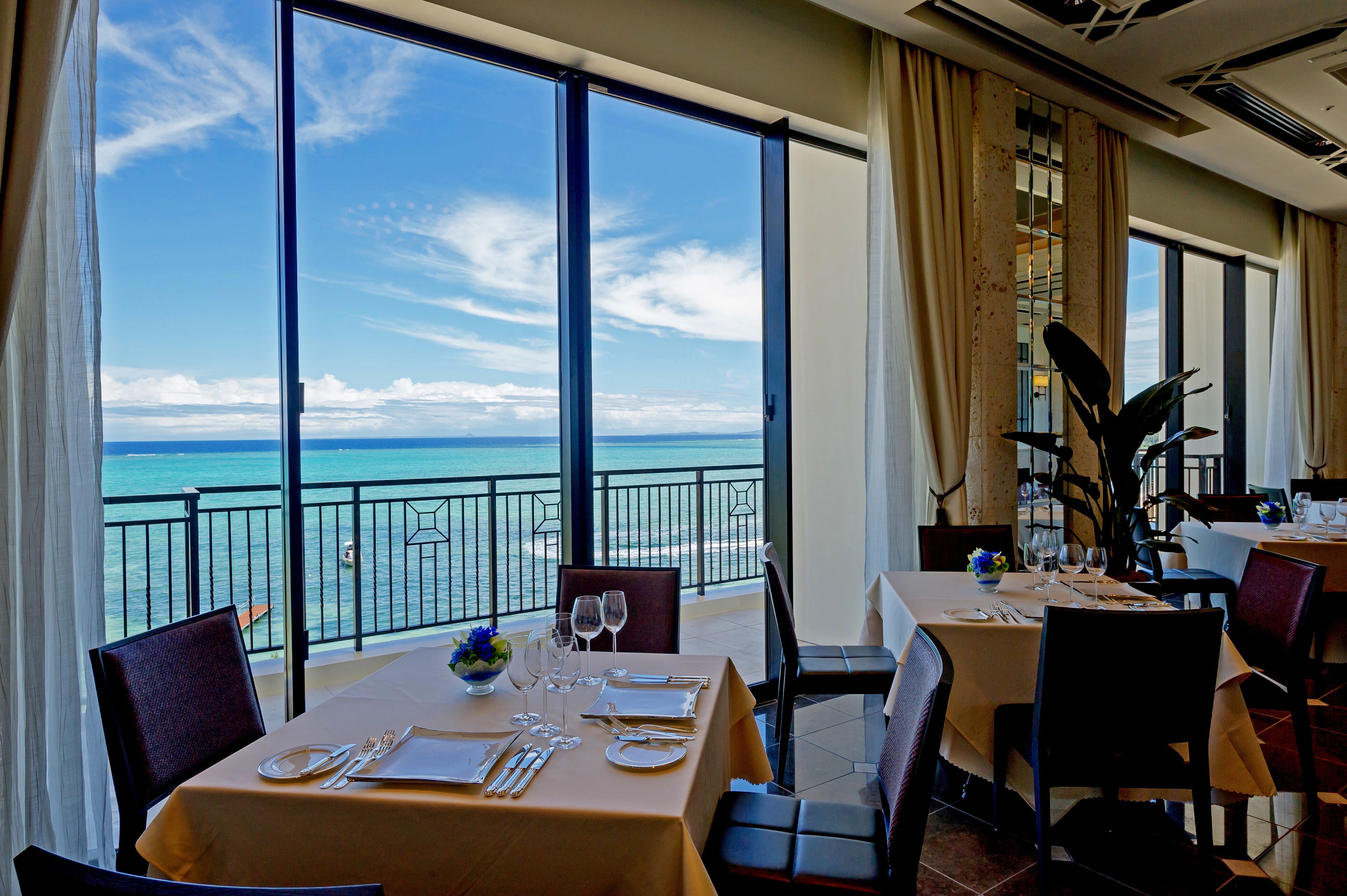 A dining area with a table set for two, overlooking a scenic ocean view.