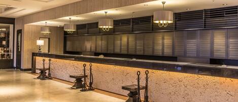 A modern hotel lobby with a reception desk, pendant lighting, and a stone accent wall.